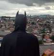 Jovem fantasiado de Batman olhando para o horizonte de casas do Capão Redondo.  Foto: PerifaCon / Divulgação / Estadão