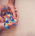 Mãos que prendem a fita do enigma para a consciência do autismo   Foto: iStock