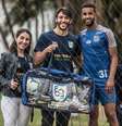 Manuella Carvalho e André Georges, da Football for a cause, e o lateral Jorge, do Santos: doação de materiais para projetos sociais  Foto: Football for a cause/Divulgação / Estadão