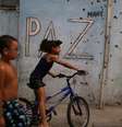 Crianças brincam diante de muro cravejado de tiros  Foto: REUTERS / BBC News Brasil