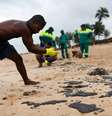 Moradores ajudam a limpar óleo da praias de Barra de Jacuipe, na Bahia  Foto: Lucas Landau / Reuters