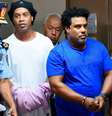 Ronaldinho e Assis chegaram algemados, antes da audiência com a Justiça  (Norberto DUARTE / AFP)  Foto: LANCE!