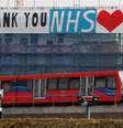 A Docklands Light Railway train is seen passing a banner on a construction site thanking the NHS, as the spread of the coronavirus disease (COVID-19) continues, London, Britain, April 8, 2020. REUTERS/Andrew Couldridge - RC2F0G9HPIV2  Foto: Reuters