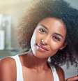 Mulher negra penteando o cabelo com uma escova e olhando para a câmera  Foto: Getty Images / Alto Astral