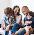 Casal multiracial, com dois filhos, sentados em um sofá  Foto: Shutterstock / Alto Astral