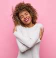Mulher se abraçando em um fundo rosa  Foto: Shutterstock / Alto Astral