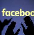 Silhueta de pessaos usando telefones celulares em frente à projeção do logotipo do Facebook. 28/3/2018.  REUTERS/Dado Ruvic  Foto: Reuters