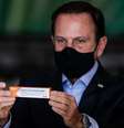 O governador de São Paulo, João Doria, apresenta a embalagem da CoronaVac, desenvolvida pelo laboratório chinês Sinovac e testada no Brasil pelo Instituto Butantan. A taxa de eficácia dessa candidata ainda não é conhecida  Foto: Rodrigo Paiva/Getty Images / BBC News Brasil