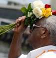 Imagem mostra homem negro, de branco, pronto para jogar flores no mar.  Foto: Imagem: Tomaz Silva/Agência Brasil / Alma Preta
