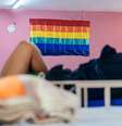 Imagem mostra bandeira LGBTI+ em destaque pendurada em uma parede rosa dentro de um dormitório de uma casa de acolhimento  Foto: Imagem: Reprodução/Casa Florescer / Alma Preta