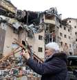 Uma mulher usa um smartphone em frente a um prédiob residencial destruído por bombardeios recentes, enquanto a invasão russa da Ucrânia continua, na cidade de Irpin, na região de Kiev  Foto: Serhii Nuzhnenko / Reuters