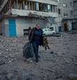 Uma mulher segura o seu cachorro na saída de um prédio residencial atingido ataques russos em Kiev, registrados nesta quarta-feira, 16  Foto: State Emergency Service of Ukraine/Handout/ / Reuters