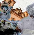 Foto mostra uma imagem de uma igreja católica ao fundo e uma mulher com vestes típicas de candomblé de costas, representando o sincretismo religioso  Foto: Imagem:  I / Alma Preta