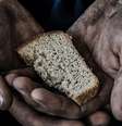 Imagem enquadra duas mãos que seguram um pedaço de pão  Foto: Shutterstock / Alma Preta