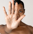 Mulher negra, em fundo branco, com a mão aberta para a câmera, simbolizando o basta de violência contra as mulheres  Foto: Imagem: Reprodução / Freepik / Alma Preta