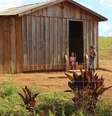 Foto de uma casa quilombola da comunidade Paiol de Telha. Na porta da moradia, estão duas crianças.  Foto: Imagem: Lizely Borges/Terra de Direitos / Alma Preta