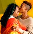 Imagem mostra duas mulheres negras envolvidas na bandeira da comunidade LGBT. Uma beija a testa da outra.  Foto: Imagem: Reprodução/Sinasefe / Alma Preta