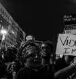 Imagem mostra mulher negra segurando cartaz contra o genocídio da população negra e em homenagem à vereadora Marielle Franco, assassinada em 2019.  Foto: Imagem: Divulgação/Mariana Maiara/Congresso em Foco / Alma Preta