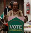 Imagem mostra Sueli Carneiro com o cartaz "Vote Antirracista", do Quilombo nos Parlamentos.  Foto: Imagem: Divulgação/Natália Carneiro / Alma Preta