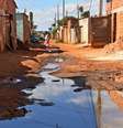 Imagem mostra rua de barro repleta de poças.  Foto: Imagem: Evaristo Sá/AFP / Alma Preta