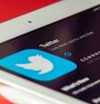 Um tablet está em cima de uma mesa cor de laranja. Na tela está a App Store em fundo preto, o ícone do Twitter e o botão de download, simbolizado pelo contorno de uma nuvem.  Foto: Souvik Banerjee / Unsplash