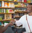 Imagem mostra cliente e caixa de supermercado, ambos homens negros, representando a preferência, apontada por relatório, dos brasileiros por empresas que apoiam a diversidade.  Foto: Imagem: Kampus Production/Pexels / Alma Preta