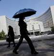 Pedestres caminham em frente ao Banco do Povo da China, em Pequim  Foto: Reuters