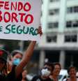 A imagem mostra uma manifestante segurando o cartaz escrito: não sou mãe e defendo o aborta legal e seguro  Foto: Imagem: Pilar Olivares/Reuters / Alma Preta