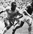 Na imagem, Pelé, um jogador negro, driblando durante um jogo de futebol Tarcisio Burgnich, jogador branco. Foto em preto e branco, estão em um estádio de futebol, na final da Copa de 1970, no México.  Foto: Imagem: STAFF/AFP / Alma Preta