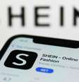 Imagem mostra aplicativo da Shein em celular e logo da marca chinesa ao fundo da imagem  Foto: NurPhoto/Getty Images / BBC News Brasil