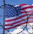 Cerca de arame farpado com a bandeira dos EUA ao fundo  Foto: Getty Images / BBC News Brasil