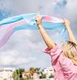 Imagem mostra pessoa segurando bandeira transgênero.   Foto: iStock