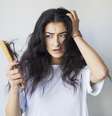 Mulher assustada com cabelo na escova  Foto: Hazal Ak / iStock