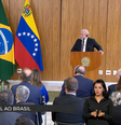 Imagem mostra Lula, à direita, e Maduro, à esquerda. Ambos vestem ternos escuros, estão atrás de pulpitos de madeira e são observados por uma plateia. Entre eles aparecem as bandeiras do Brasil e da Venezuela.  Foto: Aos Fatos