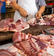 Funcionário cortando pedaços de animais em açougue  Foto: CanvaPro