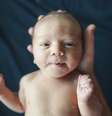 Bebê pequeno tem sua cabeça segurada por mão humana e olha diretamente para a câmera  Foto: Getty Images / BBC News Brasil