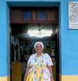 Imagem mostra a ialorixá mãe Eloísa de Badé, zeladora do terreiro. Ela está com vestimentas brancas e na entrada do espaço.  Foto: Fernando Assunção / Alma Preta