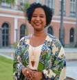 Imagem mostra Ana Flávia Magalhães, diretora do Arquivo Nacional. Ela é uma mulher negra, com cabelos ondulados, pretos e cursos. Ela usa brincos verdes, colar dourado e um kimono colorido.  Foto: Tomaz Silva/Agência Brasil / Alma Preta