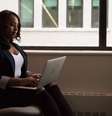Imagem mostra uma mulher negra sentada em uma poltrona e usando um notebook.  Foto: WOCInTech/Nappy / Alma Preta