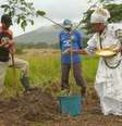 Dois homens e uma mulher em um campo aberto, de mato seco e montanhas ao fundo. A mulher usa vestimentas de religiões afro.  Foto: Divulgação / Alma Preta