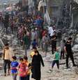 Palestinos caminham entre os escombros de edifícios destruídos  Foto: AFP / BBC News Brasil