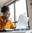 Mulher em frente a tela de um computador lendo o edital e um concurso.   Foto: Foto:Istock