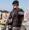 Imagem mostra policial da Rota de costas e segurando uma arma.  Foto: Alma Preta
