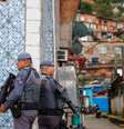 Imagem mostra dois policiais segurando fuzis.  Foto: Alma Preta