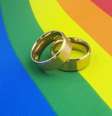 Imagem mostra a bandeira do movimento LGBTQIA + com duas alianças em cima.  Foto: Alma Preta