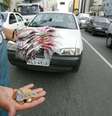 Imagem mostra um homem segurando balas e moedas que vende na rua.  Foto: Alma Preta
