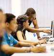 Imagem mostra um jovem negro orientando outra jovem negra diante do computador  Foto: Alma Preta