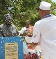 Imagem mostra um homem negro, de religião de matriz africana, reverenciando a estátua de Mãe Gilda.  Foto: Alma Preta