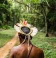 Imagem mostra homem indígena de costas caminhando em Aldeia Pataxó.  Foto: Alma Preta