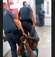 A imagem mostra dois policiais militares carregando um homem negro amarrado pelos pés e mãos.  Foto: Alma Preta